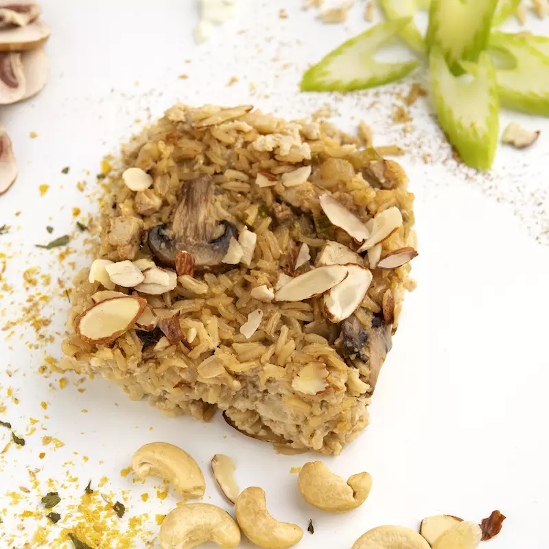 Square of almond chick'n rice on white surface with mushroom decoration