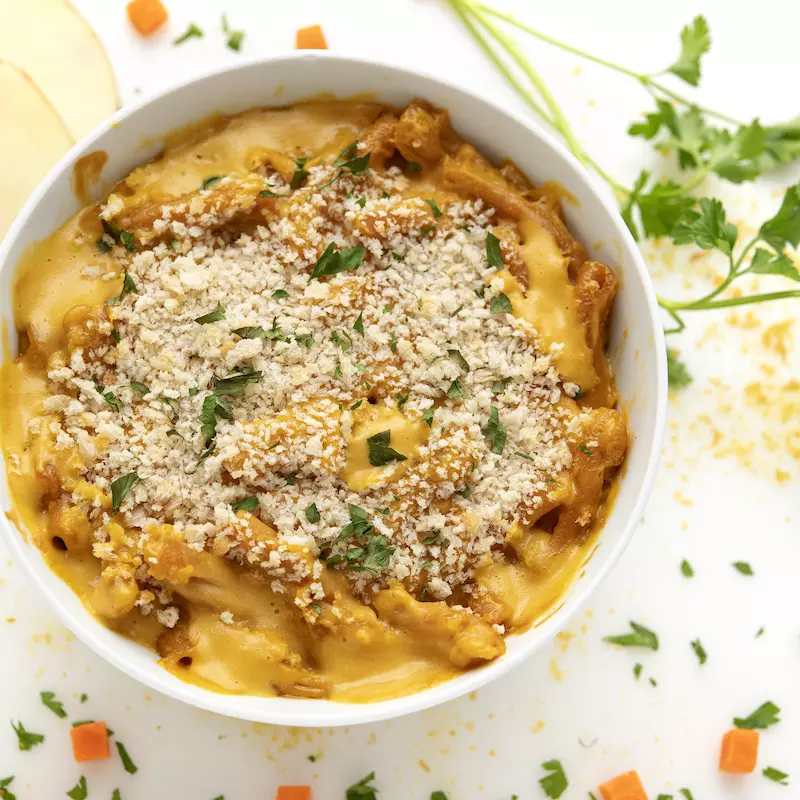 Bowl of mac and cheese with potato and parsley garnish