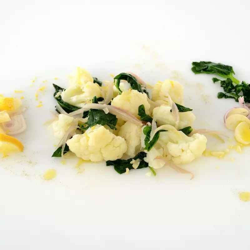 cooked cauliflower mixed with wilted spinach and onions, with lemon on the side 