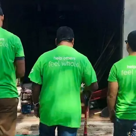 3 volunteers in green shirts facing away from the camera