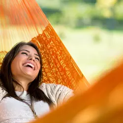 A woman relaxes in a hammock outdoors.