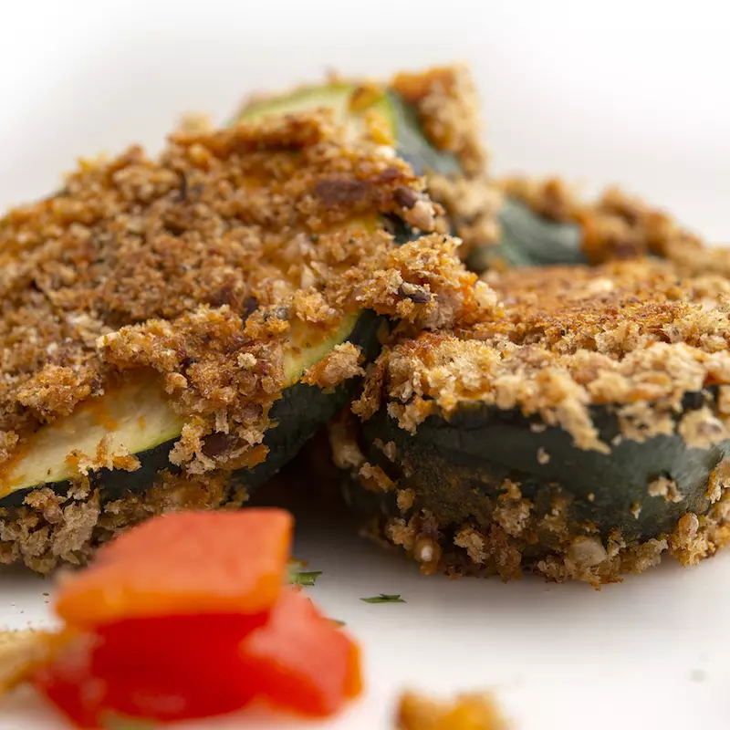 Three crusted zucchini fritters with tomato garnishes