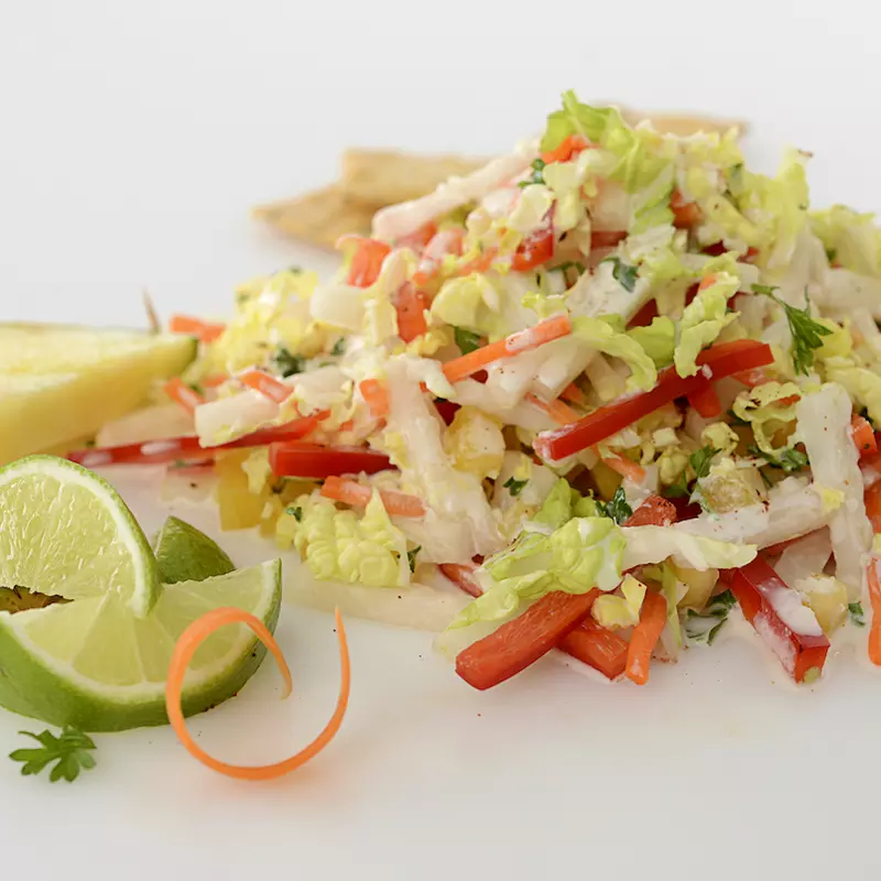 Mound of slaw with lime and pineapple wedges