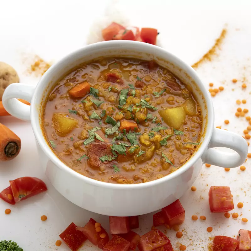 Bowl of lentil soup with carrot garnishes