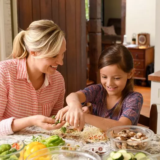 A mom teaches her daughter a recipe in the kitchen