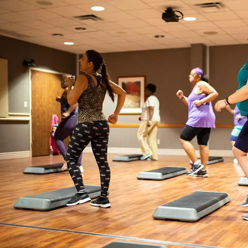 A group of women taking a step class at the gym.