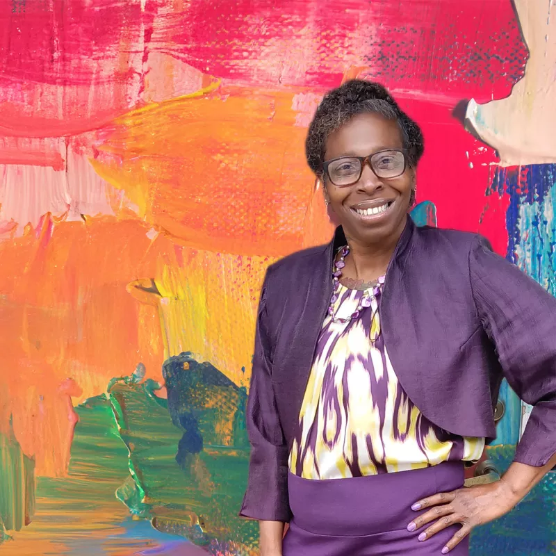 Denise Giles in front of a painterly background.