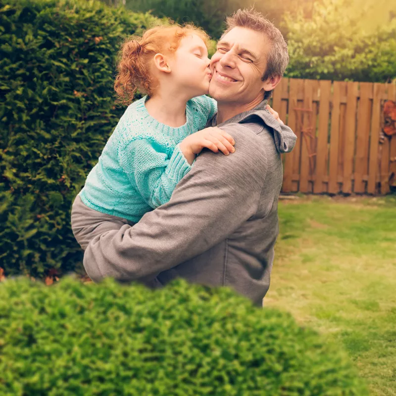 daughter hugging and kissing father outside