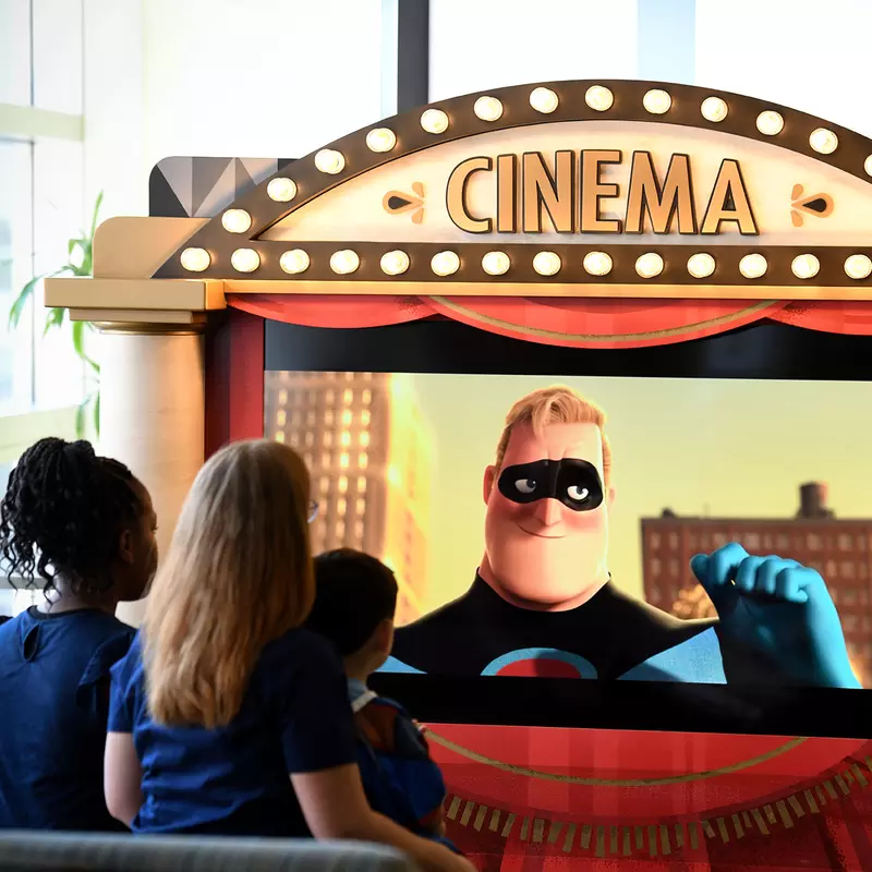 Children watching The Incredibles on a Disney Team of Heroes Mobile Movie display.