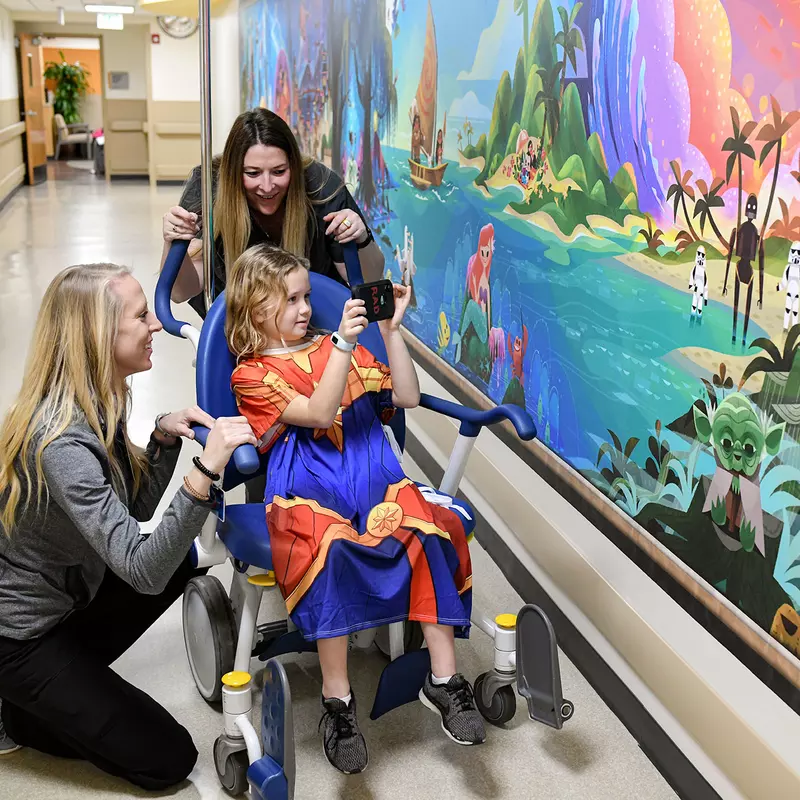 AdventHealth for Children employees showing a little girl how to use a Magic Mural