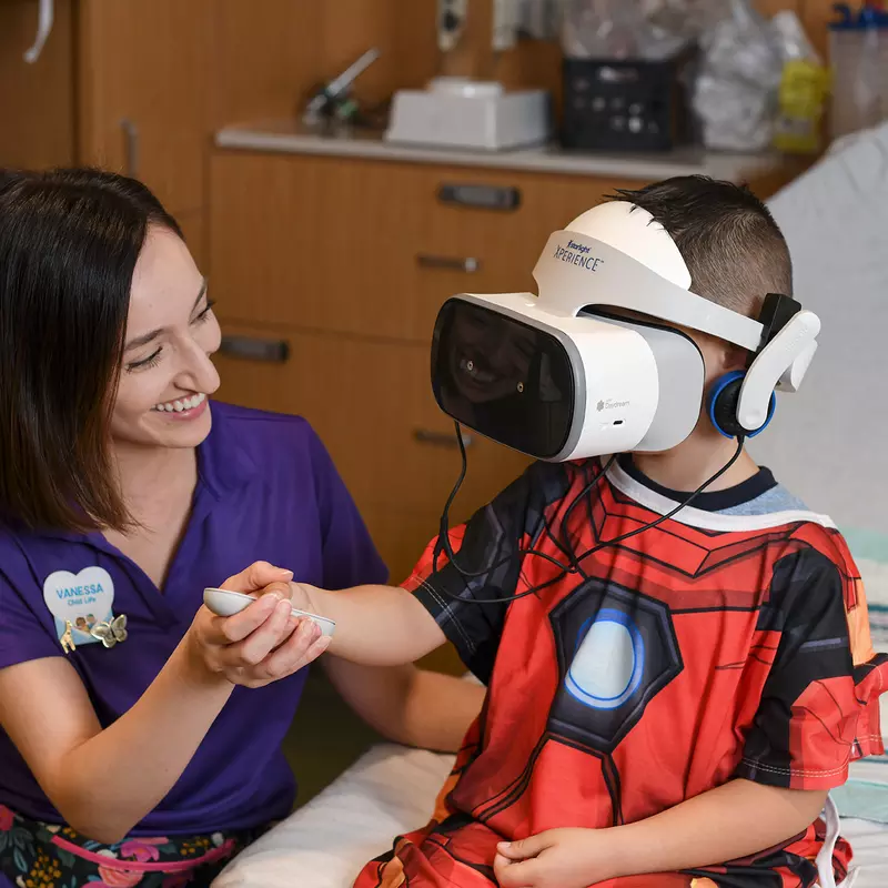 Boy using a Disney Team of Heroes Virtual Reality headset with a AdventHealth for Children staff member.