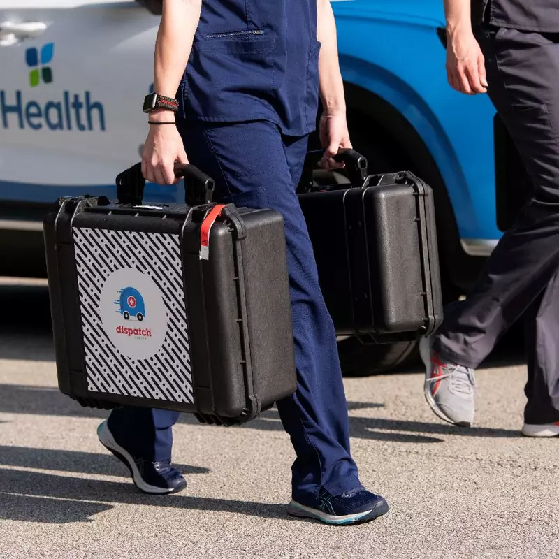 2 people in scrubs carry medical equipment in DispatchHealth cases