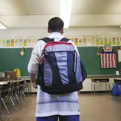 child wearing backpack in a classroom