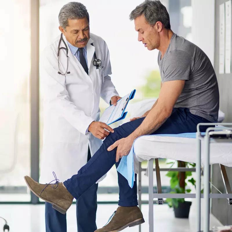 Doctor checking a male patient's knee. 