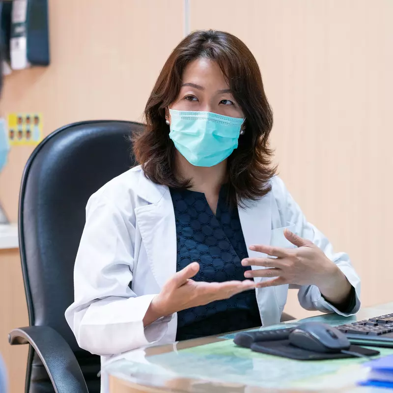 A doctor and patient during an office visit wearing masks.