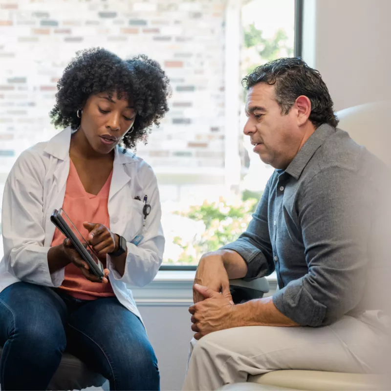 A female doctor showing a male patient test results in a examination room.