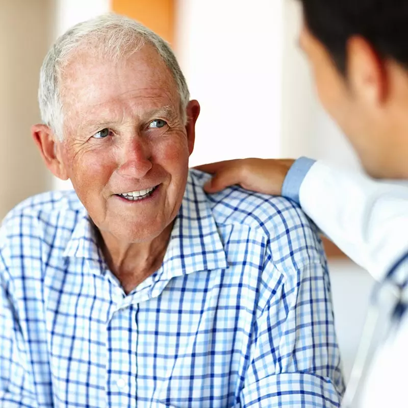 Doctor with his hand on an elderly man's shoulder