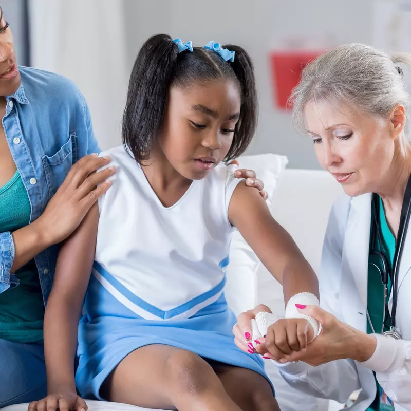 Doctor checking the arm of a young cheerleader.