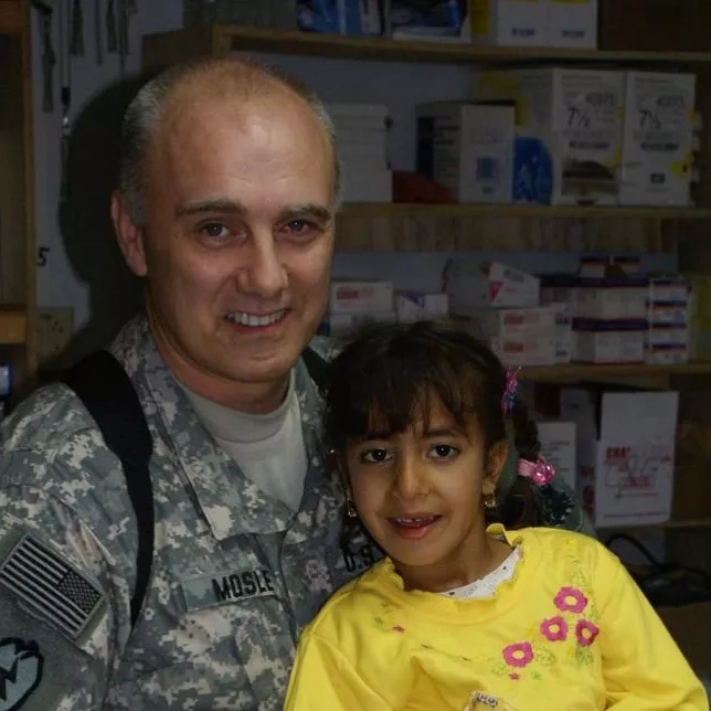 Dr. E. Wayne Mosley served seven tours in Afghanistan and Iraq as a combat physician with the U.S. Army. He's pictured here with a young patient in Mosul, Iraq. Photo Courtesy of Dr. E. Wayne Mosley