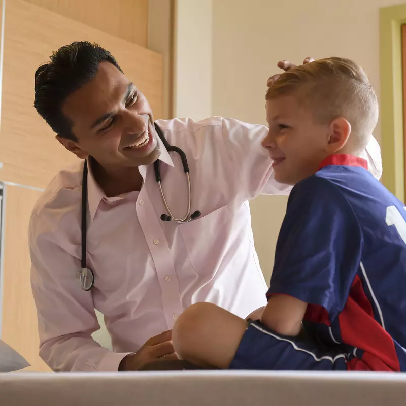 physician attending to a young boy in a medical setting