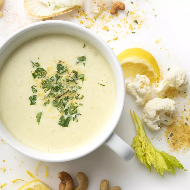 Bowl of cream of cauliflower soup with celery and breadcrumb garnish