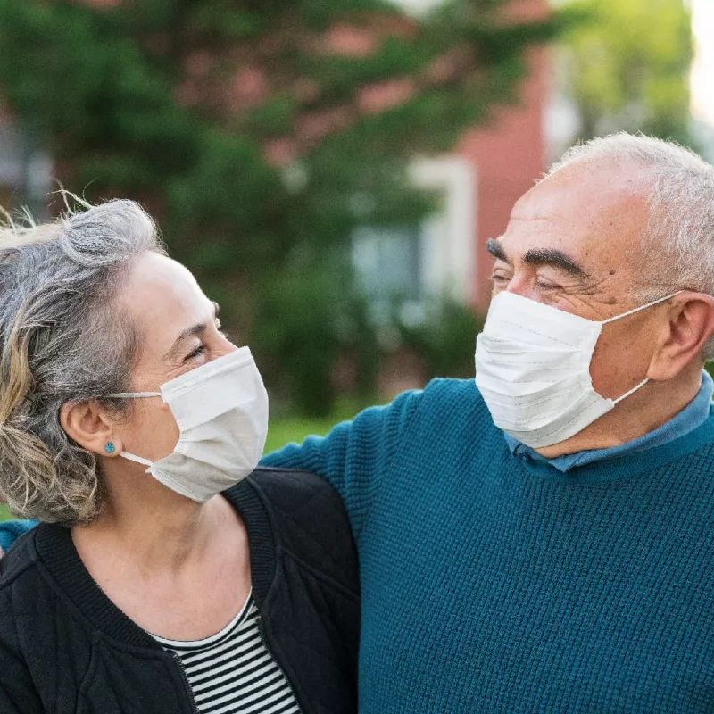 older couple wearing masks outdoors.