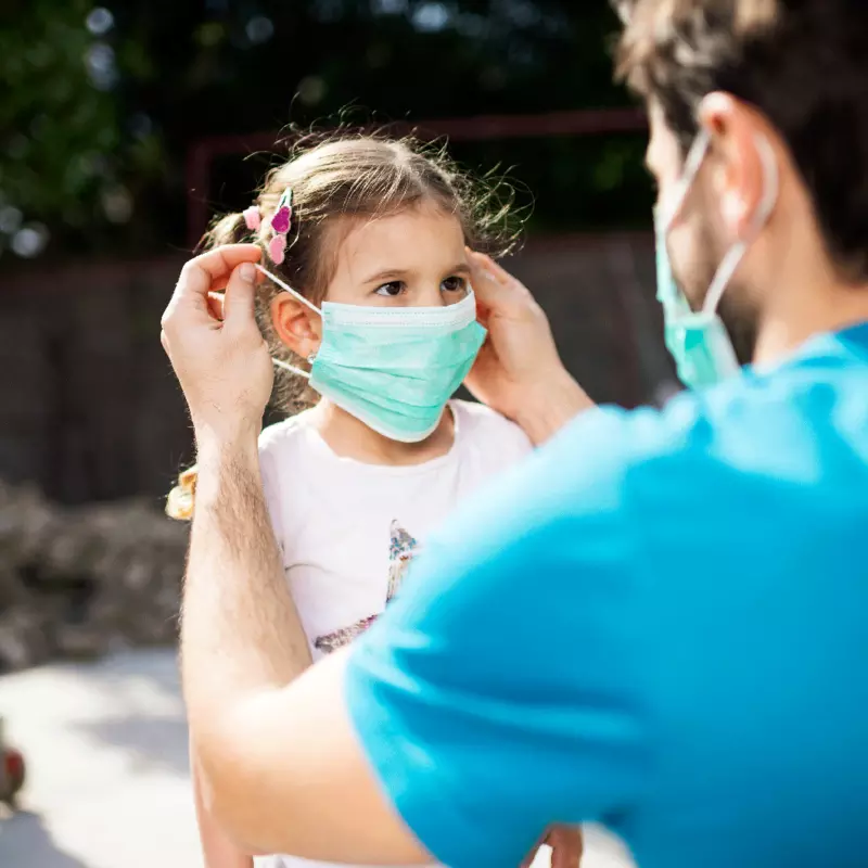 A father putting on a mask for his daughter
