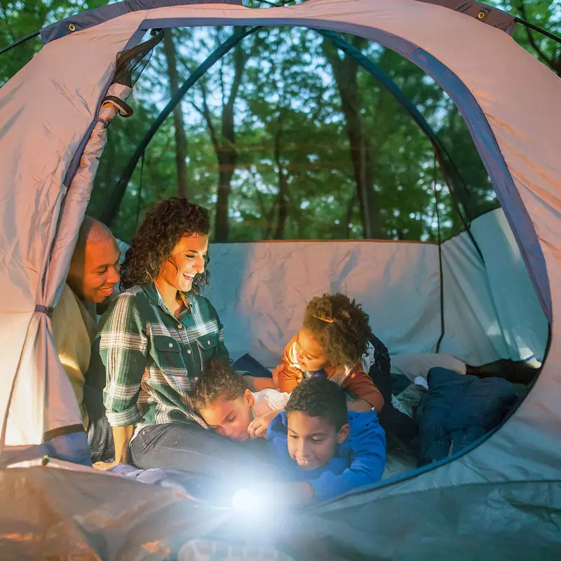 A family seating inside the tent while camping in the forest.