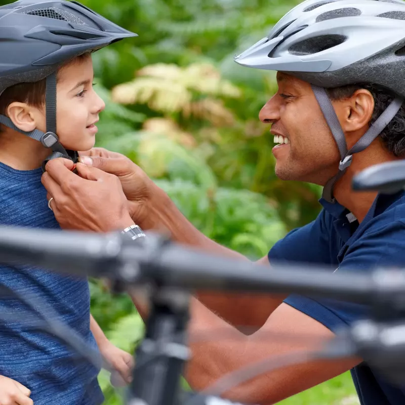 A dad adjusts his son's helmet before a bike ride