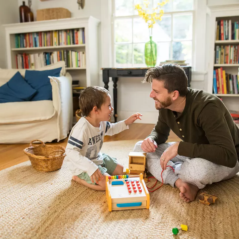 A dad playing a board game with his son in the family room.