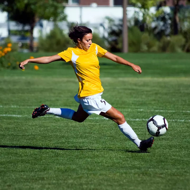 A female soccer playing kicking a soccer ball