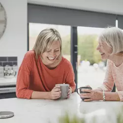 Two women laughing together at a kitchen table