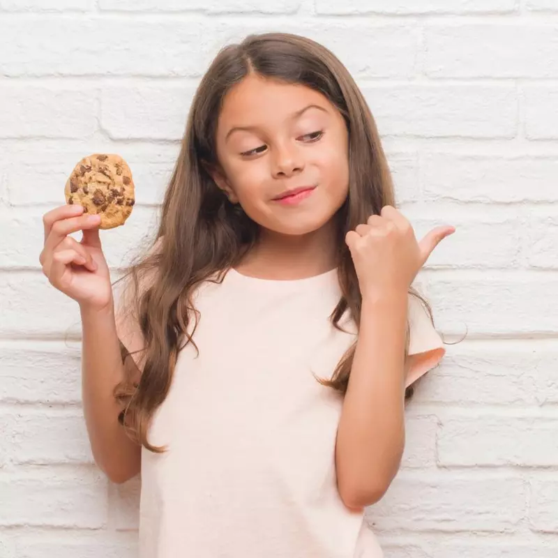 A girl smiling and holding a cookie.