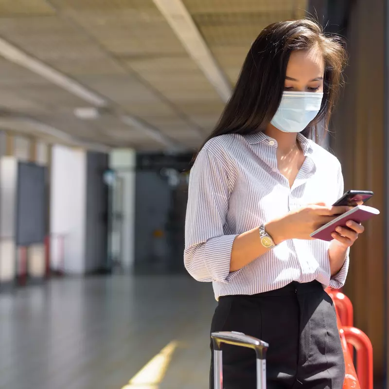 Masked woman checking her phone at an airport