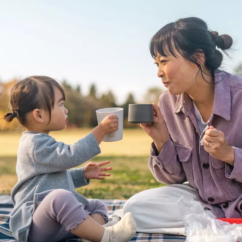 A Mother and Daughter Sit at a Picnic Enjoying Tea