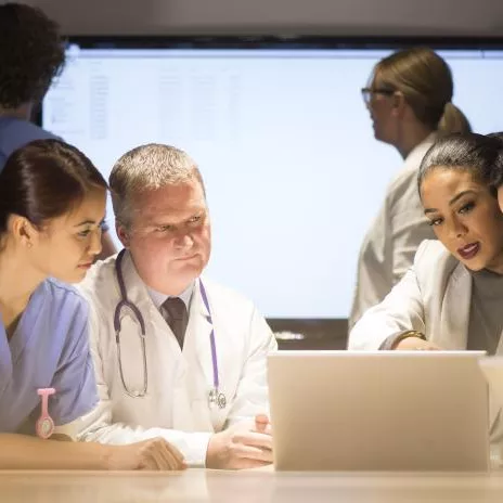 Doctors Huddle Around a Laptop Going Over Research