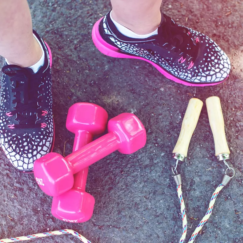 Close-up of workout shoes, weights, and a jump rope.