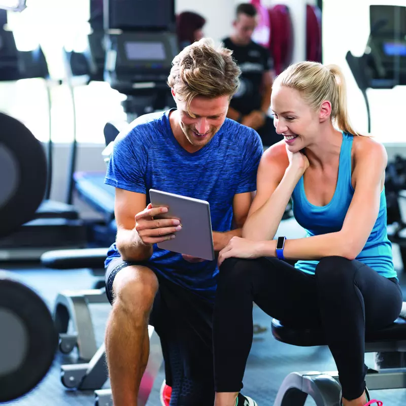 Young woman reviewing a workout plan with her trainer in the gym.