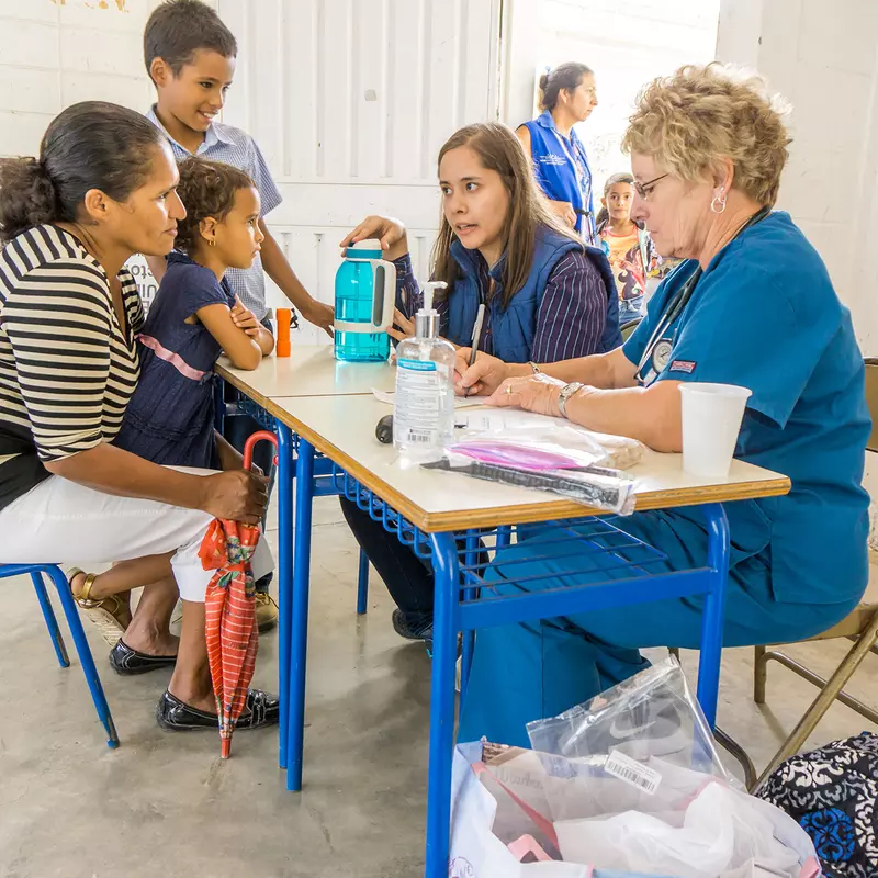 Two nurses talking to a mother with her two children