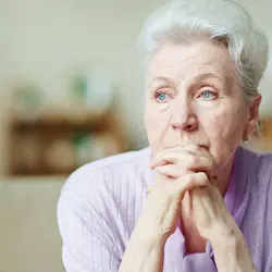 An older woman with a thoughtful look on her face.