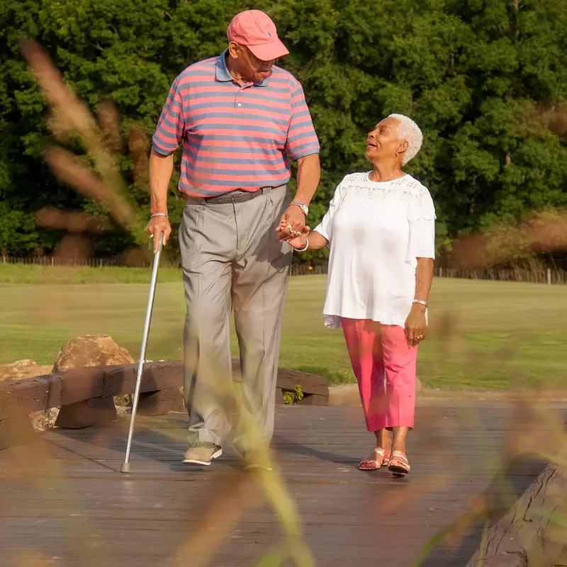Elderly couple holding hands while walking.