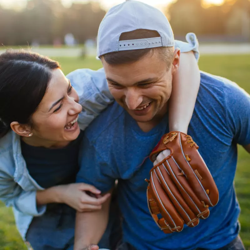 A woman and a man hugging on a baseball field.