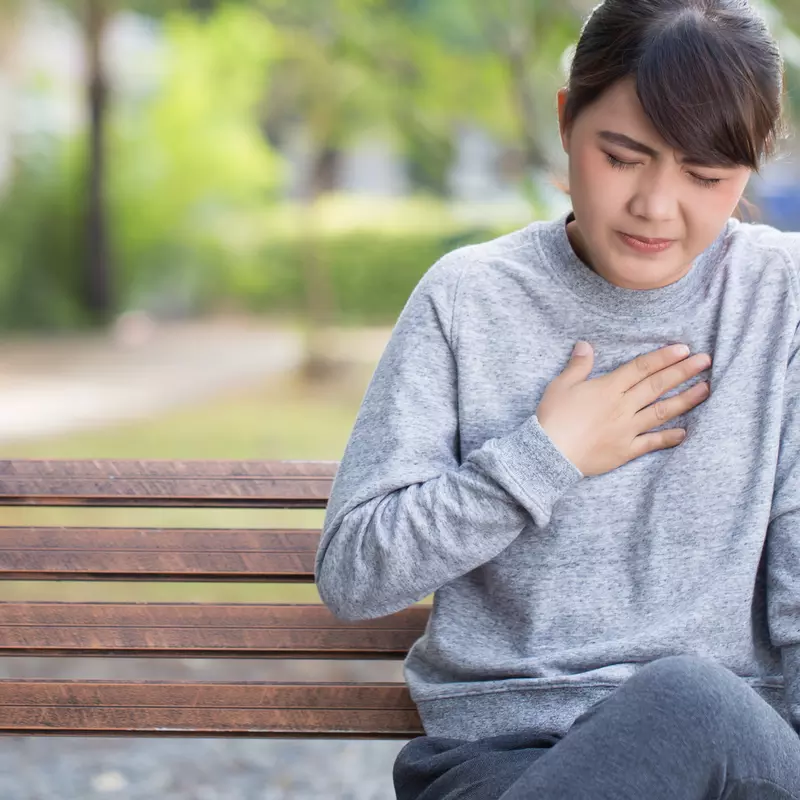 Woman experiencing heart burn in a park