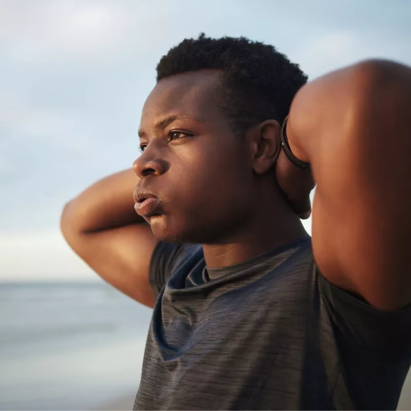 A teenage boy with a frustrated expression looks out over the ocean.