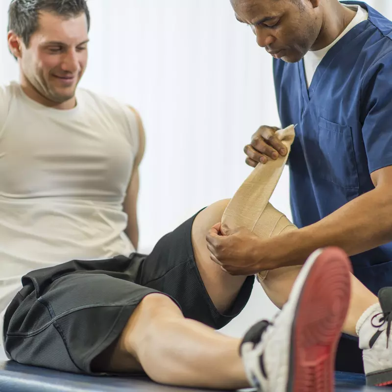 An athlete works with a physical therapist for a knee injury.