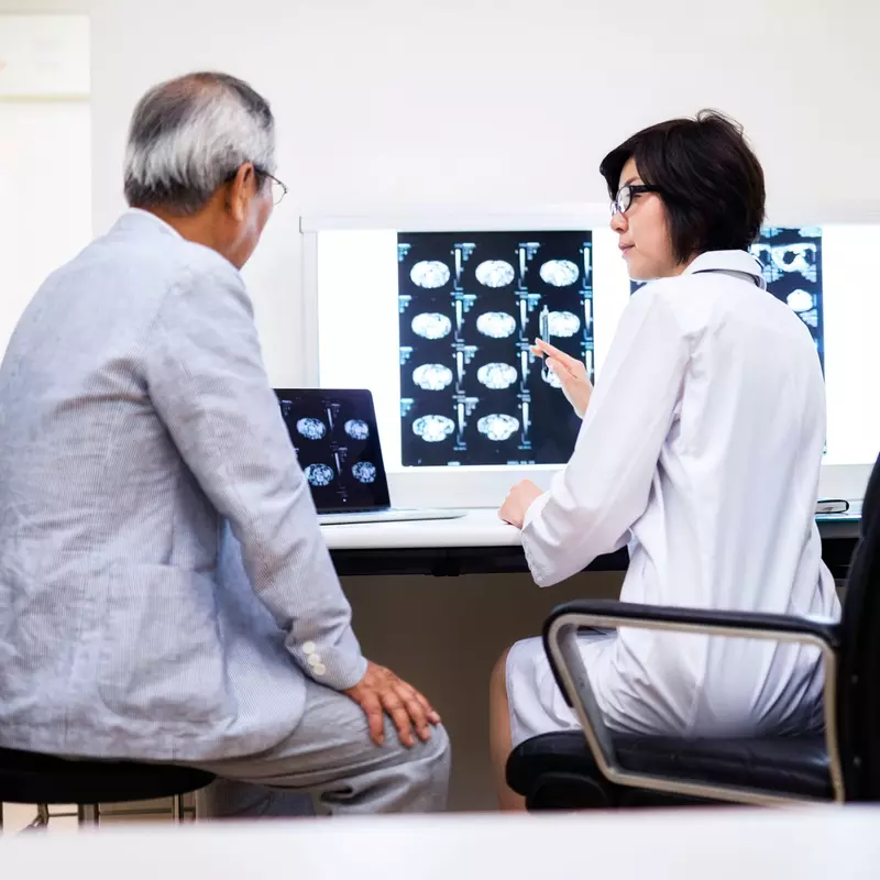 A doctor reviews brain scans with the older male patient