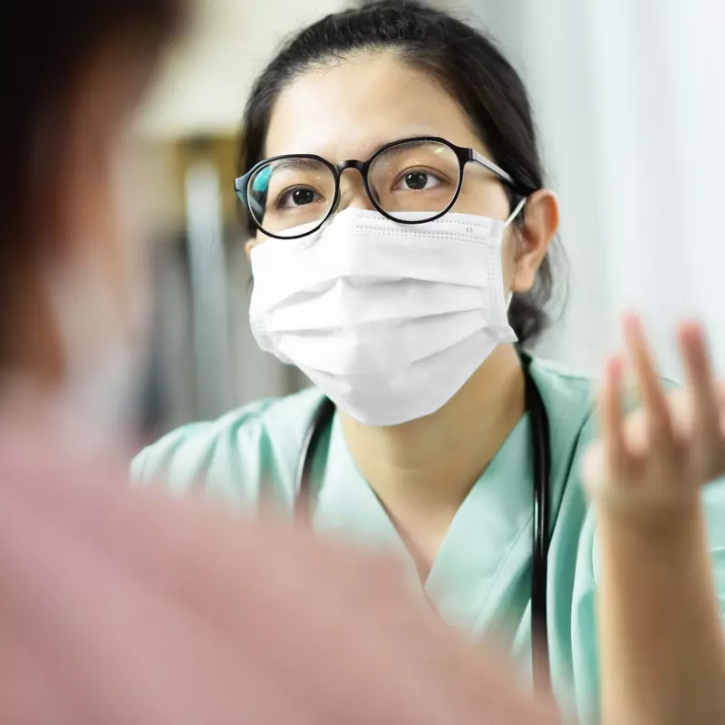 A doctor wearing a mask speaks with a patient. 