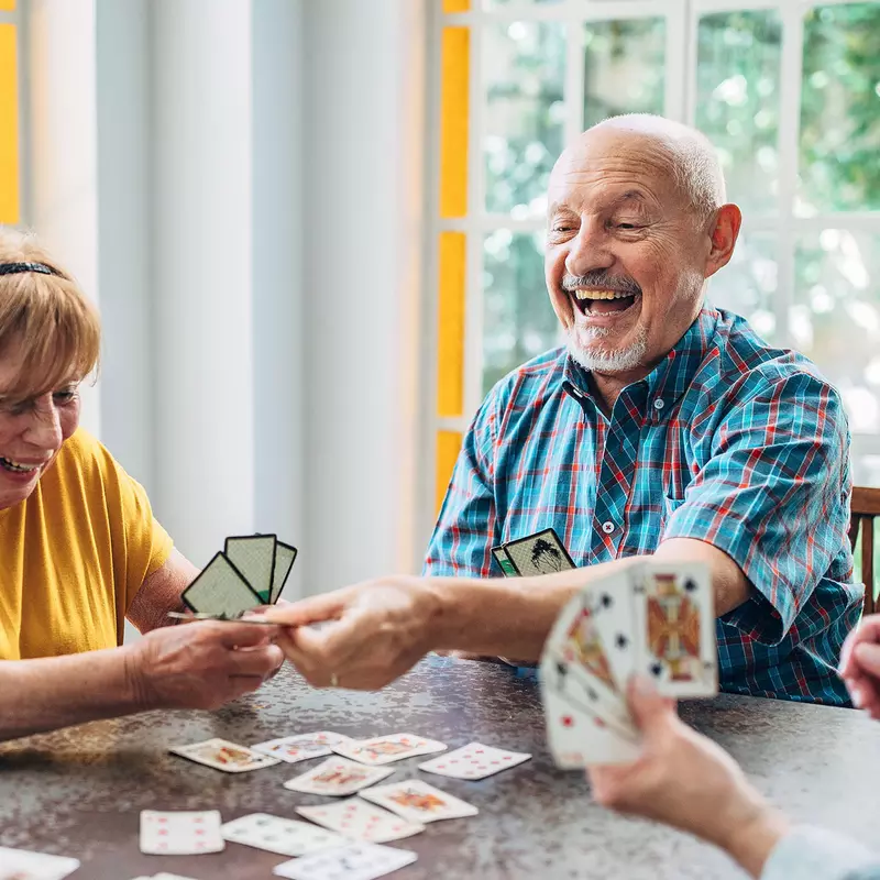 A group of senior adults play cards at home