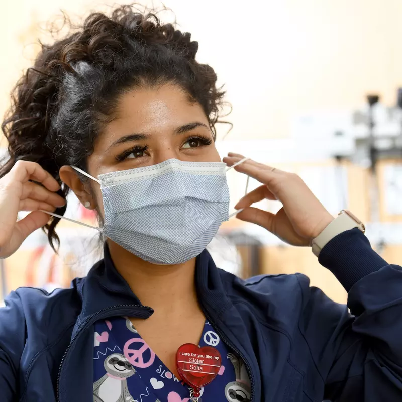 An AdventHealth employee puts on her face mask. 