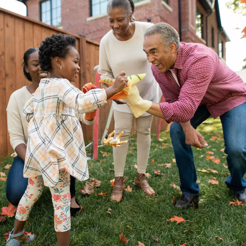 A family plays in the backyard during the fall.